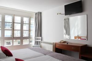 sypialnia z łóżkiem, biurkiem i telewizorem w obiekcie Hotel Hórreo by Bossh! Hotels w Santiago de Compostela