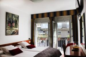 sypialnia z łóżkiem, stołem i oknami w obiekcie Hotel Hórreo by Bossh! Hotels w Santiago de Compostela +37 zdjęć