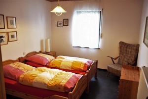 1 Schlafzimmer mit 2 Betten, einem Stuhl und einem Fenster in der Unterkunft Ferienwohnung Seidenfaden in Karlstadt
