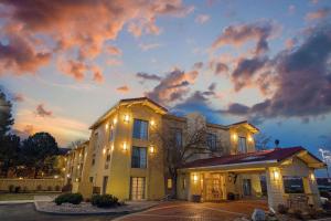 a building with lights on in front of a sunset at La Quinta Inn by Wyndham Denver Golden in Golden