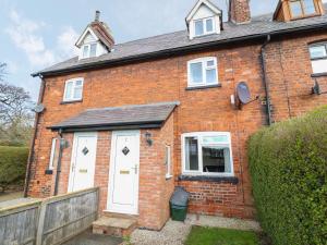 a brick house with white doors and a fence at 2 Organsdale Cottages in Kelsall Hill