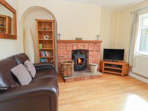 a living room with a couch and a fireplace at 2 Organsdale Cottages in Kelsall Hill