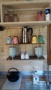 a kitchen shelf with bowls and utensils on it at Le Petit Rias en Roulotte, 4 personnes, coin cuisine et cabinet de toilette in Saint Maurice en Chalencon