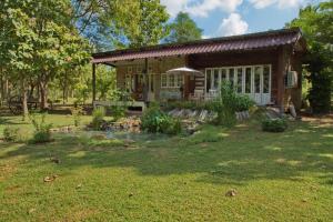 a log cabin with a yard with a pond at Cozycomo Khonkhan in Khon Kaen