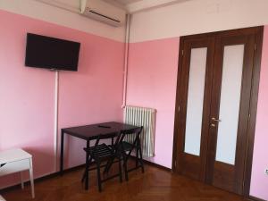 a room with a table and a tv on a pink wall at New Life in Mestre