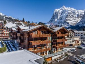 a building with a snow covered mountain in the background at Apartment Stotzhalten 3.5 - GriwaRent AG in Grindelwald
