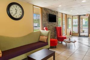 une salle d'attente avec un canapé et un réveil sur le mur dans l'établissement Pocono Inn & Banquet - Stroudsburg, à Delaware Water Gap