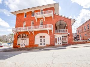 a red brick building with a balcony on a street at The Belmont Inn by OYO in Abbeville