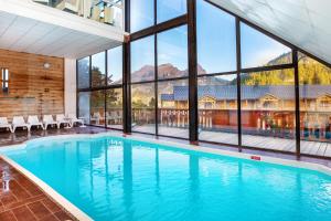 a swimming pool in a house with glass windows at SOWELL Family Les Bergers in Pra-Loup