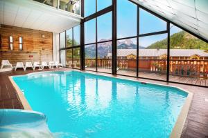 - une grande piscine dans un bâtiment doté de fenêtres dans l'établissement SOWELL Family Les Bergers, à Pra-Loup