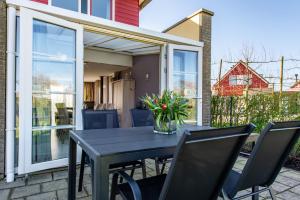 a table with chairs and a vase of flowers on a patio at Maxime 203 - Kustpark Village Scaldia in Hoofdplaat