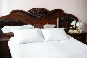 a large white bed with a wooden headboard and white pillows at Family apartment in the heart of Rivne in Rivne