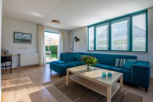 a living room with a blue couch and a table at Fréjus 116 - Kustpark Village Scaldia in Hoofdplaat