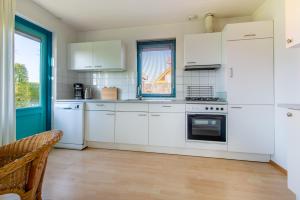 a white kitchen with white appliances and a window at Fréjus 116 - Kustpark Village Scaldia in Hoofdplaat