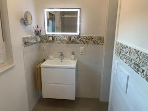 La salle de bains blanche est pourvue d'un lavabo et d'un miroir. dans l'établissement Ferienwohnung Susanne, à Bad Krozingen