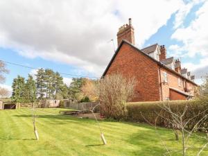a brick house with a grass yard in front of it at 1 Organsdale Cottages in Kelsall Hill