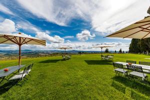 uma mesa e cadeiras com guarda-sóis num campo em Tenuta di Montecucco - ColleMassari Hospitality em Cinigiano