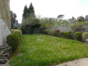 einen Garten mit Gras und Blumen und einem Zaun in der Unterkunft Ker Corentine, maison de charme à Benodet, jardin in Bénodet