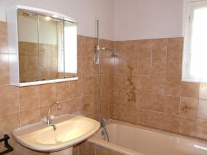 La salle de bains est pourvue d'un lavabo, d'une baignoire et d'un miroir. dans l'établissement Laraon, maison à Pouldreuzic, à Pouldreuzic