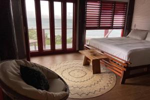 1 dormitorio con 1 cama, 1 silla y 1 ventana en Private Oceanfront Fijian Villa Sleeps 8 en Malolo