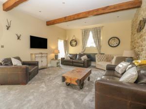 a living room with leather couches and a tv at Skyfell in Skipton