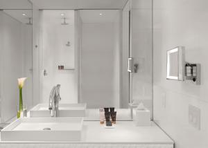 a bathroom with a sink, mirror and bath tub at SLS Brickell in Miami