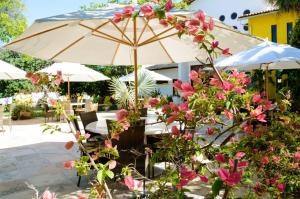 un tavolo con un ombrello e dei fiori rosa di Refúgios Parajuru a Parajuru