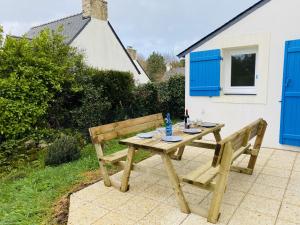 een houten picknicktafel en bank voor een huis bij Voile et Plage, Villa 3 étoiles à La Trinité sur Mer in La Trinité-sur-Mer