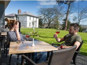 ein Mann und eine Frau sitzen mit Weingläsern an einem Tisch in der Unterkunft Cardigan Castle in Cardigan