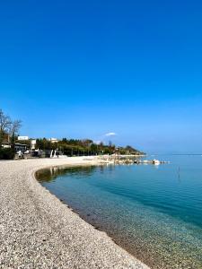 a beach with blue water and a rocky shore at Albergo La Pescatrice in Moniga