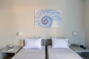 two beds in a room with a painting on the wall at SPLASH with amazing Sea Views in Piso Livadi in Piso Livadi