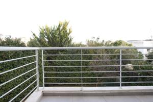 une clôture sur un balcon avec des arbres en arrière-plan dans l'établissement Voula, A modern, minimal and stylish, apartment, à Athènes