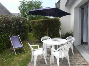 una mesa y sillas con una sombrilla en el patio en Dran Ty en Carnac