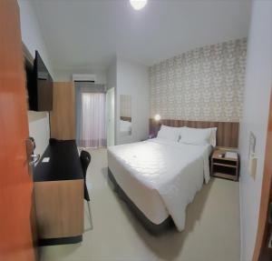 een slaapkamer met een groot wit bed en een televisie bij Hotel Horto in Rondonópolis