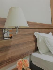 uma cama com um candeeiro numa cabeceira de madeira em Hotel Horto em Rondonópolis
