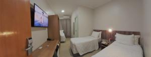 a hotel room with two beds and a flat screen tv at Hotel Horto in Rondonópolis