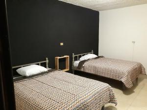 een slaapkamer met 2 bedden en een zwarte muur bij Posada Loreto Xalapa in Xalapa