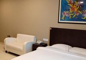 a hotel room with a bed and a chair at Hotel Desaru Penawar in Desaru