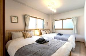a bedroom with two beds and two windows at Secret House - 2 min to FuSe station - in Osaka