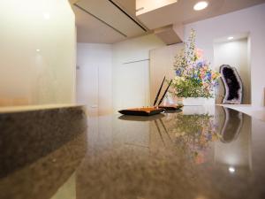Zimmer mit einem Tisch und einer Blumenvase in der Unterkunft Moriyama Art Hotel in Moriyama