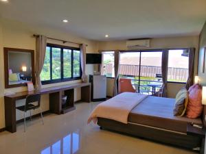 a bedroom with a bed and a desk and windows at ศรีกรุงดีลักซ์โฮเตล in Phra Nakhon Si Ayutthaya