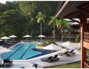 a swimming pool with lounge chairs and umbrellas at Redang Island Resort in Redang Island