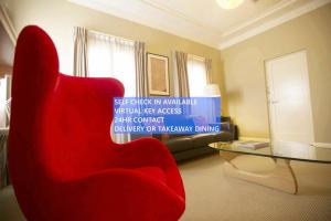 a living room with a red chair and a table at Globe Apartments in Wagga Wagga