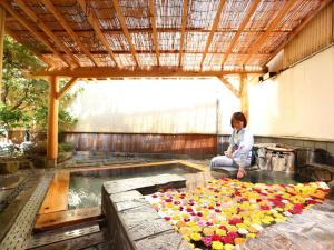 una mujer sentada frente a una piscina de flores en Kamiyamada Hotel, en Chikuma