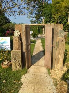 an entrance to a garden with wooden doors and clocks at Nong Or Blue House Resort in Sukhothai