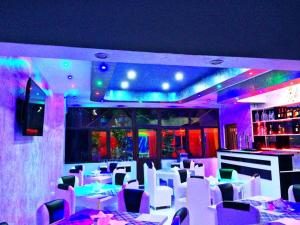 un ristorante con tavoli e sedie bianchi e illuminazione viola di Golden House a Batumi