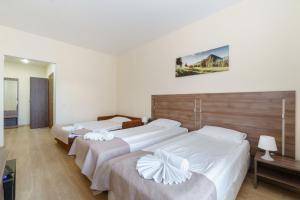 two beds in a hotel room with white sheets at Meridian Hotel in Saint Petersburg