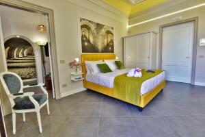 a bedroom with a large bed and a chair at ANFITEATRO LE SUITES in Catania