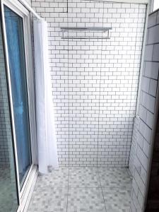 um chuveiro de azulejos brancos com uma janela na casa de banho em Westgate Residence Hotel em Ban Bang Kho