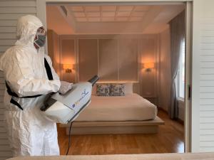 a person in a hazmat suit standing next to a bed at K Maison Boutique Hotel in Bangkok